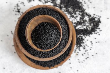 Hint baharatlı kimyon (nigella sativa veya kalonji) tohumları tahta kaselerde fotokopi alanı ile üst görünümde. Geleneksel tıp, sağlıklı ve vejetaryen gıda konsepti.