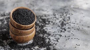 Hint baharatlı kimyon (nigella sativa veya kalonji) tohumları gri masadaki ahşap kaselerde fotokopi alanına yakın. Geleneksel tıp, sağlıklı ve vejetaryen gıda konsepti.