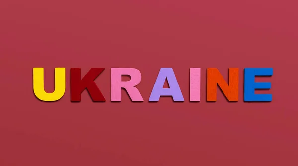Ukraina Słowo Napisane Kolorowymi Drewnianymi Literami Alfabetu Czerwonym Tle Koncepcja — Zdjęcie stockowe
