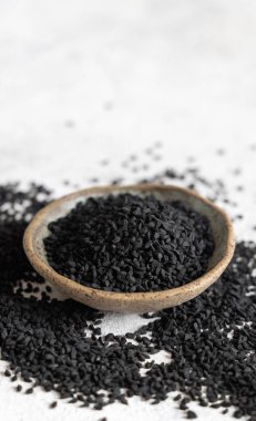 Hint baharatlı kimyon (nigella sativa veya kalonji) tohumları gri masada, fotokopi alanı ile yakın plan. Geleneksel tıp, sağlıklı ve vejetaryen gıda konsepti.