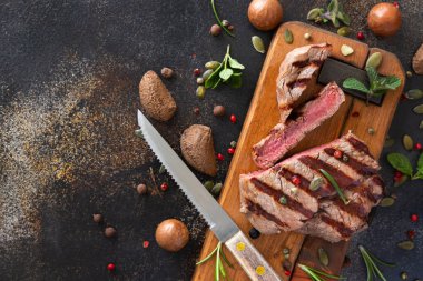 Izgara biftek bifteği, koyu masanın üstünde. Üst manzaraya yakın. Baharat ve otlarla porsiyonlu fileminyon. Yaz yemeği kavramı, et yiyiciler. 