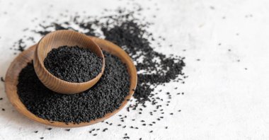 Hint baharatlı kimyon (nigella sativa veya kalonji) tohumları tahta kaselerde fotokopi alanı ile kaplıdır. Geleneksel tıp, sağlıklı ve vejetaryen gıda konsepti.