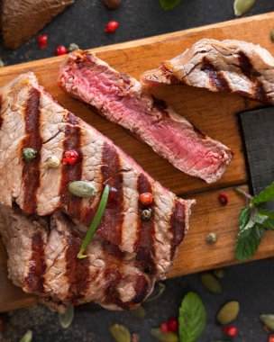 Izgara biftek bifteği, koyu masanın üstünde. Üst manzaraya yakın. Baharat ve otlarla porsiyonlu fileminyon. Yaz yemeği kavramı, et yiyiciler. 