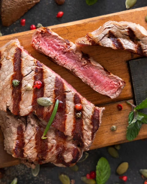 Izgara biftek bifteği, koyu masanın üstünde. Üst manzaraya yakın. Baharat ve otlarla porsiyonlu fileminyon. Yaz yemeği kavramı, et yiyiciler. 