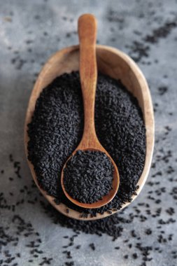 Hint baharatlı kimyon (nigella sativa veya kalonji) tohumları kasede gri masa manzaralı kaşık ile. Geleneksel tıp, sağlıklı ve vejetaryen gıda konsepti.