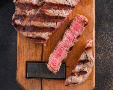 Izgara biftek bifteği, koyu masanın üstünde. Üst manzaraya yakın. Pişmiş porsiyon fileminyon. Yaz yemeği kavramı, et yiyiciler. 