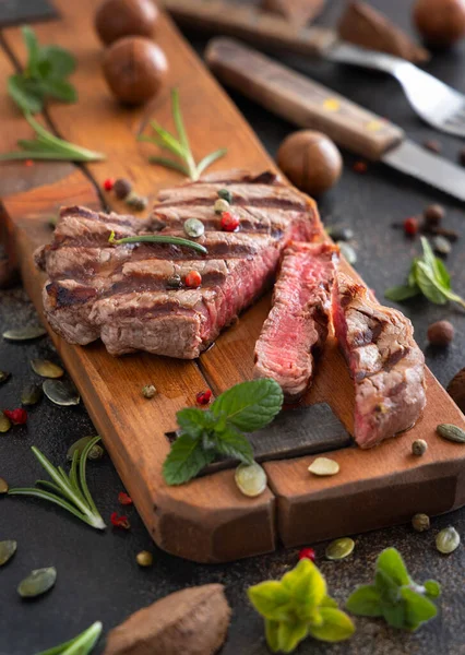 Koyu masada ızgara biftekli biftek, yakın çekim. Baharat ve otlarla porsiyonlu fileminyon. Yaz yemeği kavramı, et yiyiciler. 