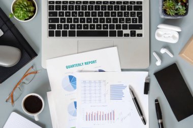 Laptop, sulu bitkiler, belgeler ve aletlerle dolu modern ofis masaüstü. Kahve fincanıyla üç aylık raporlar üzerinde çalışıyorum. Smark evde çalışıyor.