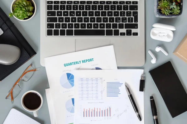 Laptop, sulu bitkiler, belgeler ve aletlerle dolu modern ofis masaüstü. Kahve fincanıyla üç aylık raporlar üzerinde çalışıyorum. Smark evde çalışıyor.