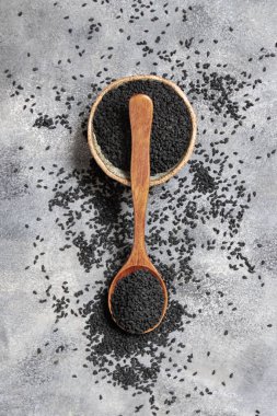 Bir kase Hint baharatlı kimyon (nigella sativa veya kalonji) tohumu, tahta kaşıkla gri masanın üzerinde, üst manzara. Geleneksel Asya tıbbı, sağlıklı ve vejetaryen gıda konsepti