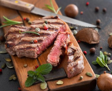 Koyu masada ızgara biftekli biftek, yakın çekim. Baharat ve otlarla porsiyonlu fileminyon. Yaz yemeği kavramı, et yiyiciler. 