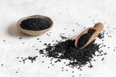 Hint baharatlı kimyon kepçesi (nigella sativa ya da kalonji) tohumları beyaz masada fotokopi alanı ile yakınlaşır. Geleneksel tıp, sağlıklı ve vejetaryen gıda konsepti.
