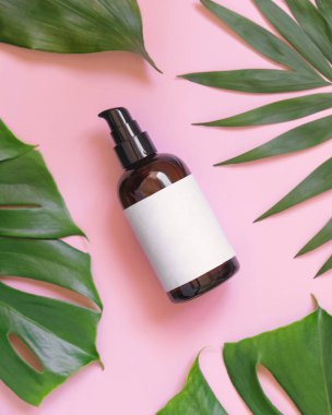 Kahverengi bir şişe, pembe üst manzaralı tropik yaprakların arasında. Marka ambalaj modeli. Doğal bitkisel kozmetik konsepti - Aromatik yağ, cilt bakım ürünü, krem veya seru