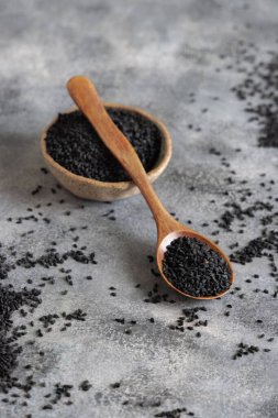 Bir kase Hint baharatlı kimyon (nigella sativa ya da kalonji) tohumları, tahta kaşıkla gri masada, kopyalama alanı ile kaplıdır. Geleneksel Asya tıbbı, sağlıklı ve vejetaryen gıda konsepti