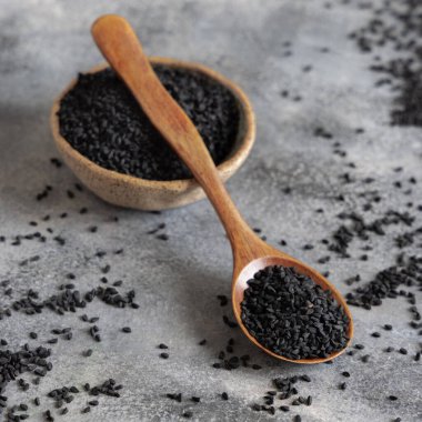 Bir kase Hint baharatlı kimyon (nigella sativa ya da kalonji) tohumları, tahta kaşıkla gri masada, kopyalama alanı ile kaplıdır. Geleneksel Asya tıbbı, sağlıklı ve vejetaryen gıda konsepti