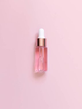 Açık pembe üzerine pembe damlacık şişesi, üst manzara, maket. Cilt bakım ürünü, Aromatik yağ ya da serum. Ev yapımı kozmetik ürünler, en az miktarda pastel bileşim.