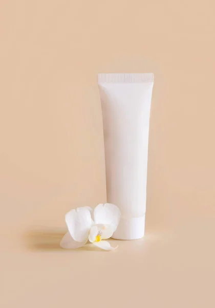 白色塑料管靠近白色兰花 浅黄色 护肤美容产品 乳霜或乳液 异国情调的天然化妆品 油腻的最低成分 — 图库照片
