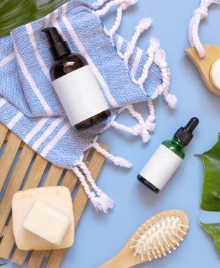 Cam bir pompa makinesi, deri ve saç bakım aksesuarları mavi banyo havlusunun üstünde, fotokopi odası. Paketleme modeli. Doğal ev yapımı ürünler