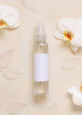 Beyaz orkide çiçeklerinin yanında açık sarı üst manzaralı bir pompa kutusu, maket. Cilt bakım ürünleri paketi. Egzotik doğal kozmetik ürünler, pastel minimum bileşik.