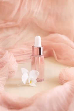 Açık pembe damlalı şişe, beyaz orkide çiçeğinin yanında açık sarı renkte, yaklaş, taklit et. Cilt bakım ürünü, Aromatik yağ ya da serum. Egzotik kozmetik ürünler, pastel minimumda kompozit.