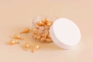 Açık sarı kavanozdaki güzellik serumu kapsülleri. Yakından. Cilt kozmetiği. Kullanmak için mükemmel dozda serumla yüz bakımı. Pastel minimal bileşimi