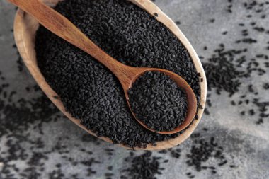 Hint baharatlı kimyon (nigella sativa veya kalonji) tohumları kasede gri masa manzaralı kaşık ile. Geleneksel tıp, sağlıklı ve vejetaryen gıda konsepti.