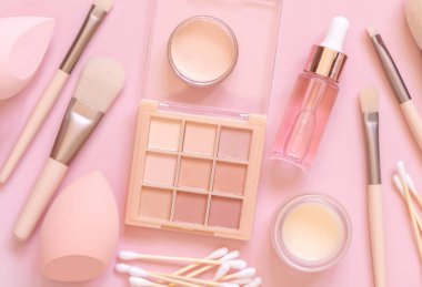 Cilt bakımı ve makyaj ürünleri açık pembe, üst görünüm, afiş. Doğal güzellik ürünleri ve dekoratif kozmetiklerle yatıyordu. Günlük kadın yüz bakımı rutini. Pastel bileşimi