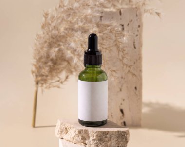 Travertin taşının üzerinde yeşil damlacık şişesi açık sarıdaki kuru otların yanında, yakın plan, maket. Cilt bakım ürünü. Doğal kozmetikler. Boho bileşimi