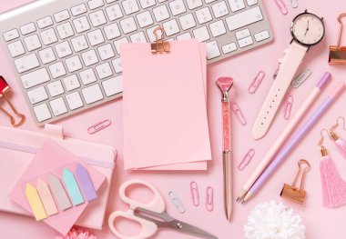 Şarjörlü kağıt, pembe okul aksesuarları ve açık pembe klavye, üst manzara, maket. Not defteri, makas, kalem, ataç, kart ve saati olan kız işyeri. Okula geri dön. 