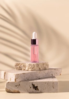 Dropper Bottle on travertine stone near white orchid flowers and palm leaf shadow on light yellow, close up, mockup. Skincare beauty product, essential oil or serum. Exotic cosmetics, pastel minimal compositio