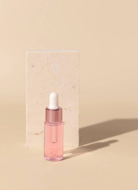 Glass cosmetic Dropper Bottle near travertine stone on light yellow, close up, mockup. Exotic skincare beauty product, essential oil or serum. Pastel minimal compositio