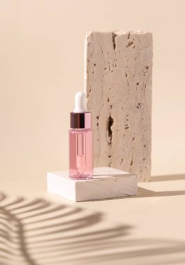 Dropper Bottle on travertine stone near white orchid flowers and palm leaf shadow on light yellow, close up, mockup. Skincare beauty product, essential oil or serum. Exotic cosmetics, pastel minimal compositio