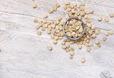 Bowl of raw dry Grass pea on wood top view. Healthy, protein source for vegan and vegetarian diet. Traditional Italian apulian cuisine ingredient. Legumes known as Cicerchia, Vetch, Blue Sweet Pea