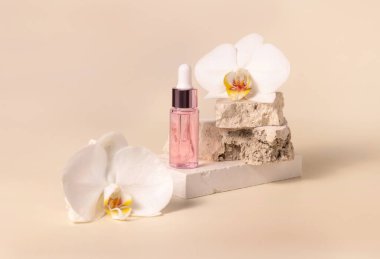 Dropper Bottle on stone near white orchid flowers on light yellow, close up, mockup. Skincare beauty product, essential oil or serum. Exotic cosmetics, pastel minimal compositio