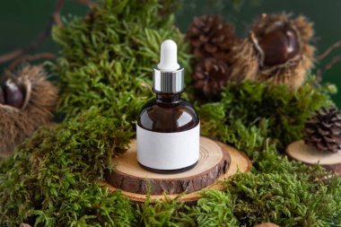 Brown glass dropper bottle with blank label on wooden piece between green moss, close up, mockup. Skincare beauty product package. Natural Organic Cosmetic concept