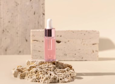 Glass cosmetic Dropper Bottle on travertine stone on light yellow, close up, mockup. Exotic skincare beauty product, essential oil or serum. Pastel minimal compositio