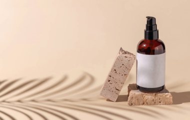 Brown Glass cosmetic one pump bottle on travertine stone on light beige. Palm leaf hard shadows, close up, label mockup. Skincare beauty product, lotion or essence. Natural cosmetic