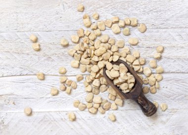 Scoop of raw dry Grass pea on wood top view. Healthy, protein source for vegan and vegetarian diet. Traditional Italian apulian cuisine ingredient. Legumes known as Cicerchia, Vetch, Blue Sweet Pea