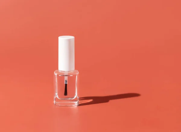 Clear Glass Refillable Bottle with Brush Cap on pink, hard shadow, close up, mockup. Skincare or nail product. Natural cosmetics, minimal compositio