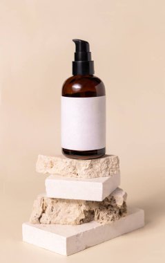 Brown cosmetic one pump bottle with blank label on beige travertine stones on light yellow, close up, Skincare beauty product Mockup. Natural eco friendly cosmetics, minimal composition