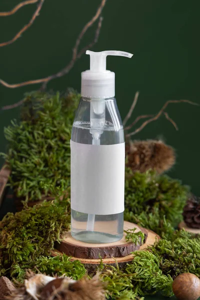 White Refillable Cosmetic Pump Dispenser on wooden piece between green moss, close up, mockup. Skincare beauty product package. Natural Organic Cosmetic concept