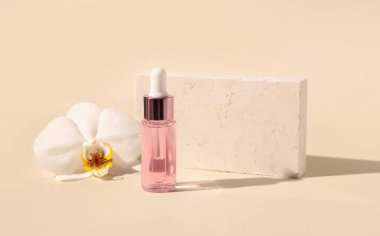 Light Pink Dropper Bottle with serum near white orchid flower on light yellow, close up, mockup. Skincare beauty product, Aromatic oil or serum. Exotic cosmetics, pastel minimal compositio