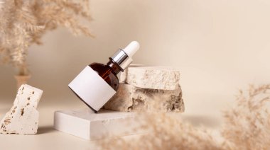 Brown dropper bottle with blank label on travertine stone near dry pampas grass on light yellow, close up, mockup. Skincare beauty product. Natural cosmetics. Boho compositio