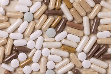 Mix of medical capsules and pills on light beige top view. Preventive medicine and healthcare, taking dietary supplements and vitamins.  Assorted pharmaceutical medicine capsules
