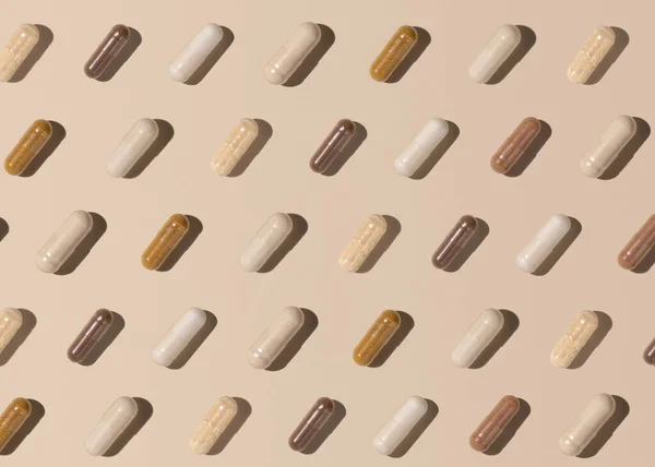 Capsules on light beige top view, hard shadows, creative pattern. Preventive medicine and healthcare, taking dietary supplements and vitamins.  Assorted pharmaceutical medicine capsules