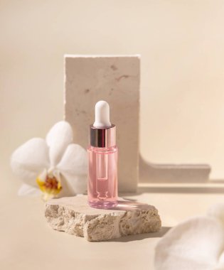 Dropper Bottle on stone near white orchid flowers on light yellow, close up, mockup. Skincare beauty product, essential oil or serum. Exotic cosmetics, pastel minimal compositio