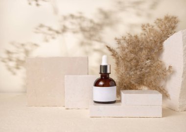 Brown dropper  bottle with blank label on stones near pampas grass on light beige close up, packaging mockup. Skincare beauty product, lotion or cleanser. Natural eco friendly cosmetics
