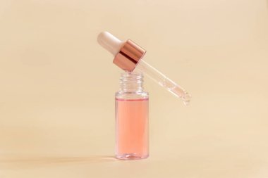 Opened Bottle with serum drop falling from pipette cap on light beige, close up, copy space. Skincare cosmetic product, essence or serum. Everyday beauty routin