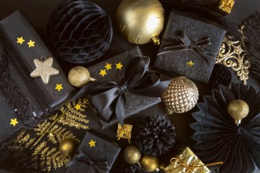 Christmas Gift Box with a bow near black and golden ornaments and baubles top view. Dark winter flat lay for Christmas, New Year, Birthday, Anniversary 