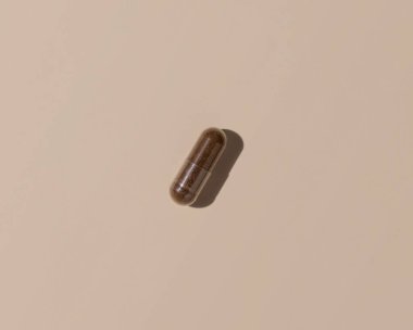 Açık bej üst görüşlü kahverengi tıbbi kapsül, sert gölgeler. Koruyucu ilaç ve sağlık, beslenme takviyeleri ve vitaminler. En düşük bileşim